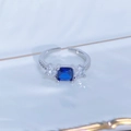Top view of sea blue square zircon ring with side stones on a white ceramic plate - Adjustable Open / Square Blue Gemstone Style (JZ5181)