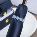 Detalle de anillo plateado ajustable con flores azules sobre fondo con textura - Abierto Ajustable / Estilo de Anillo en Fila de Flores Esmalte Azul (JZ0806A)