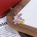 Détail d'une bague dorée avec papillons en émail violet et incrustation de zircons - Style Triple Papillon Émail Violet (JZ2064A)