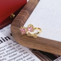 Détail d'une bague dorée avec pierres cœur roses et nœud scintillant sur un plateau - Style Nœud Cœur Rose (JZ3214A)