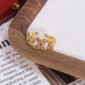 Vue macro d'une bague dorée vintage avec motifs fleurs en émail violet sur lin blanc - Style Motif Nuage Ruyi Violet (JZ6081)