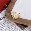 Gros plan d'une bague papillon dorée avec perles et émail sur fond de lin blanc - Style Double Couche Perle Papillon Blanc (JZ6255)
