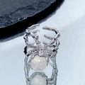 Vue détaillée d'une bague araignée argentée avec opale sur fond réfléchissant - Ouvert Réglable / Araignée en Argent Pierre Oeil de Chat Blanche (JZ1960)