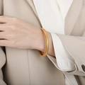 Polished gold snake bone elastic bracelet for women on model wearing beige suit - Gold
