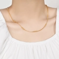 Minimalistische 24K vergulde kralenketting getoond als een delicate choker bij een model - Goud (LL016)