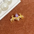 Gros plan d'une bague couronne dorée avec pierre violette sur fourrure brune - Ouvert Réglable / Couronne Gemme Goutte d'Eau Violette (JZ6106)
