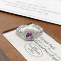 Macro shot of silver ring with purple zircon stone and pavé diamonds in a jewelry box - Adjustable Open / Rectangular Purple Stone Halo Style (JZ6273)
