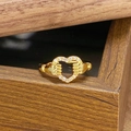 Makro-Detail eines goldenen Vintage-Herzrings mit Zirkonia-Inlay auf Holztextur-Hintergrund - Einstellbar Offen / Hände Bewachen Herz Stil (JZ1575)