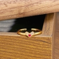 Detailansicht eines goldenen Vintage-Rings mit Zirkonia-Herz auf Walnussholz - Einstellbar Offen / Roter Stein Herz Pavé Stil (JZ5744)