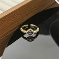Dettaglio ravvicinato dell'anello vintage in oro con smalto blu e giglio su superficie nera - Motivo a Giglio Blu (JZ5982)