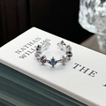 Macro detail of silver-tone ear cuff with colorful star-shaped zirconia on white book - Adjustable Open / Four-pointed Star Colorful Gemstone Ear Cuff Style (JZ1172A)