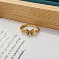 Détail de bague papillon dorée avec pierres vertes sur un socle en velours vert - Ouvert Réglable / Design Papillon (JZ3242A)