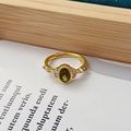 Gros plan d'une bague vintage plaquée or avec pierre verte et détails en zircon - Ouvert Réglable / Style Pierre Latérale Gemme Verte Ovale (JZ5285)