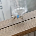 Macro detail of silver dragonfly ring with blue teardrop gemstone on wooden surface - Dragonfly Design Style (JZ4523)