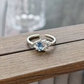 Detailed shot of an adjustable silver ring with blue oval gemstone on a wood beam - Wing Eye Design Style (JZ5371)