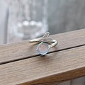 Close-up of mermaid tail open ring with iridescent gemstone on natural wood texture - Mermaid Tail Moonstone Style (JZ5509)
