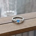 Macro shot of a heart-shaped blue zircon ring with small side diamonds on a wooden surface - Heart Blue Zircon Open Style (JZ5748)