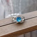 Macro detail of silver ring with round blue gemstone and pavé diamonds on wood - Double Row Round Blue Style (JZ5849)