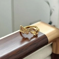 Dettaglio dell'anello a farfalla dorato con zirconi incastonati su superficie in legno - Stile Doppia Farfalla Zirconia (JZ3764A)