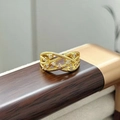 Dettaglio macro di anello intrecciato dorato con zirconi bianchi su supporto in legno - Stile Cavo Trama Multistrato (JZ4933)