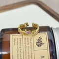 Detailansicht eines Goldrings mit violetten Emailleherzen auf einer Vintage-Glasflasche - Rebenherz Lila Emaille-Stil (JZ4320)