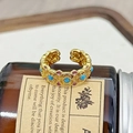 Nahaufnahme eines Vintage-Goldrings mit Türkis und lila Emaille auf einer braunen Flasche - Retro Türkis Lila Dekorativer Stil (JZ5903)