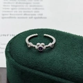 Close-up of a silver plum blossom ring with purple gemstone on a green velvet stand - Adjustable Open / Purple Round Plum Blossom Style (JZ4941)