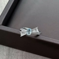 Detailed macro view of silver bow ring featuring light blue gemstone and pavé zircon stones - Adjustable Open
