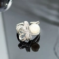 Detail of silver bow ring with shimmering cubic zirconia and a white pearl on black background - French Pearl Micro-Inlaid Bowknot Style (JZ2690)