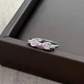 Macro shot of silver bow ring with pink heart stones and zircon accents on a display box - Adjustable Open