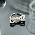 Detail of silver bow ring featuring pavé zircons and white pearls on a dark background - Pearl Rhinestone Bowknot Style (JZ3656A)