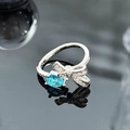 Macro shot of bow-shaped silver ring with blue pear-cut stone and micro-pavé diamonds - Blue Pear Stone Bowknot Style (JZ5054)