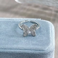 Macro shot of butterfly open ring with sparkling cubic zirconia on light blue velvet - Adjustable Open / Full Zirconia Butterfly Style (JZ3727A)