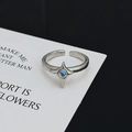Nahaufnahme eines silbernen Sternrings mit blauem Edelstein auf weißer Karte - Vierpunktstern Blauer Bunter Stein Stil (JZ1013)