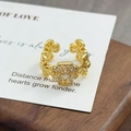 Makroaufnahme eines Vintage Gold-Blumenrings mit Zirkonia auf einem Holzständer - Komplexes Vierblättriges Kleeblatt Blumenmuster (JZ0128A)