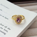 Makro-Detail des Vintage-Goldrings mit ovalem lila Edelstein und Diamant-Pavé auf einem Buch - Einstellbar Offen / Sphärische Textur Eleganter Atmosphärenstil (JZ5925) / Gold-Lila