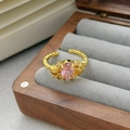Gros plan d'une bague ouverte avec zircon rose et détails de coquillages sur anneau doré - Ouvert Réglable / Style Gemme Rose Ovale et Coquillage (JZ0280A)