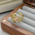 Vista macro di una gemma a cuore rosa e zirconi su un anello dorato a forma di stella - Aperto Regolabile / Stile Cuore Geometrico Stella con Zirconia Rosa (JZ3428A)