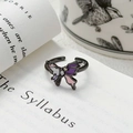 Détail d'une bague papillon vintage avec émail violet et zircons sur des pages de livre - Ouvert Réglable / Papillon Émail Dégradé Multicolore Avec Zircon (JZ4804A)