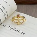 Dettaglio dell'anello vintage a arco con zircone a cuore rosa su un libro inglese - Stile Cuore Rosa Freccia di Cupido (JZ2209A)