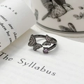 Détail d'une bague papillon vintage avec pierre violette sur des livres décoratifs - Ouvert Réglable / Double Papillon Entrelacé Avec Zircon Violet (JZ5632A)