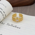 Détail d'une bague vintage dorée avec cœur ajouré posée sur un livre ouvert - Cœur en Dentelle Évidée Vintage (JZ4294)