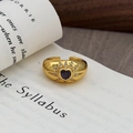 Dettaglio di un anello a cuore vintage in oro con zircone viola su un libro aperto - Stile Cuore Starburst Viola (JZ5946)