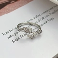 Dettaglio anello mani abbracciate argento con zirconi viola e bianchi su libro - Stile Abbraccio con Zirconia (JZ2593)