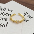 Detailansicht eines vintage gedrehten Goldrings mit Zirkonia auf einer eleganten Karte - Geknoteter Twist-Stil (JZ6093)