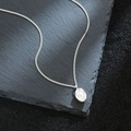 Elegant peanut pearl pendant necklace with silver chain on dark stone background - Silver