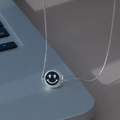 Nahaufnahme einer silbernen Schlangenkette mit schwarzem Emaille-Smiley-Anhänger - Schwarz