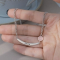Detail der silbernen Smile-Halskette mit rosa Emaille und Gravur auf dem Metallanhänger - Rosa