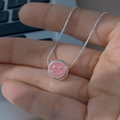Detailansicht einer silbernen Schlangenkette mit einem rosa Emaille-Smiley-Anhänger. - Rosa