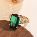 Close-up of emerald-cut green crystal ring with gold textured band and zircon accents - Gold Emerald